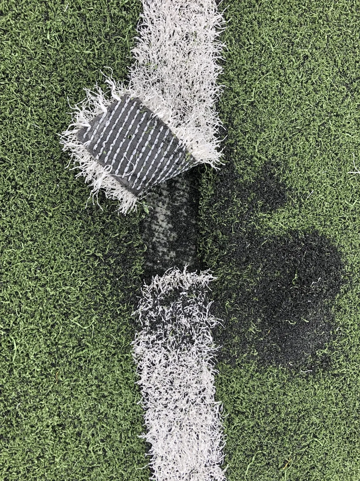 Torn turf line with backing exposed before repair
